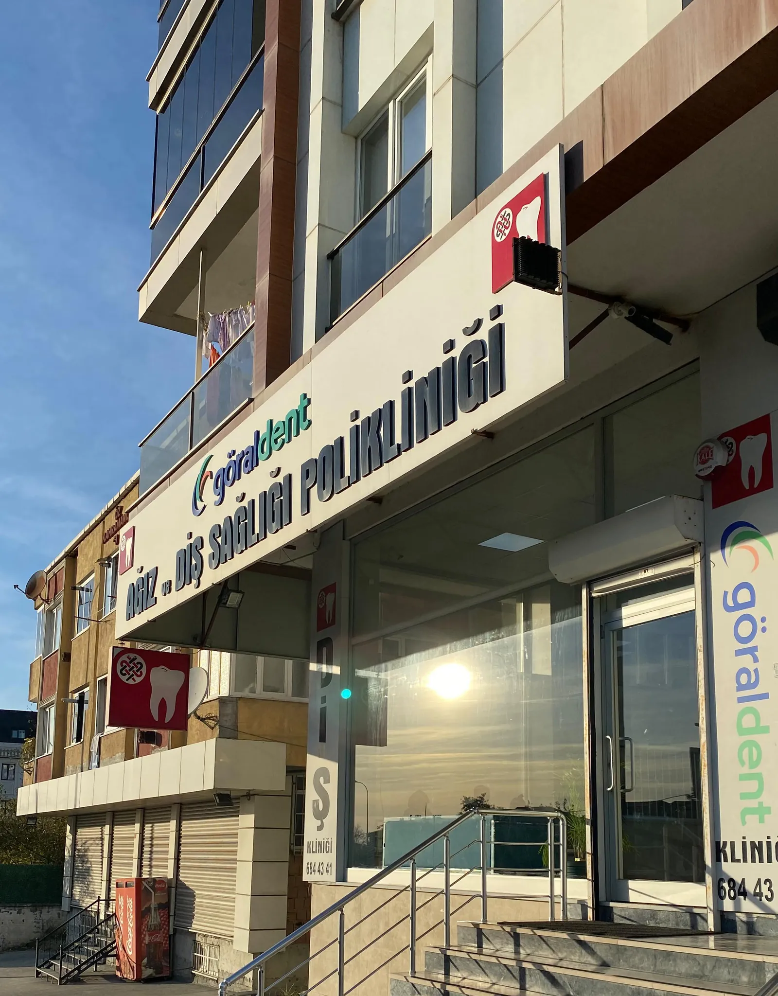 Akşamüstü ışığında klinik cephesi, üstünde ağız ve diş sağlığı polikliniği tabelası
